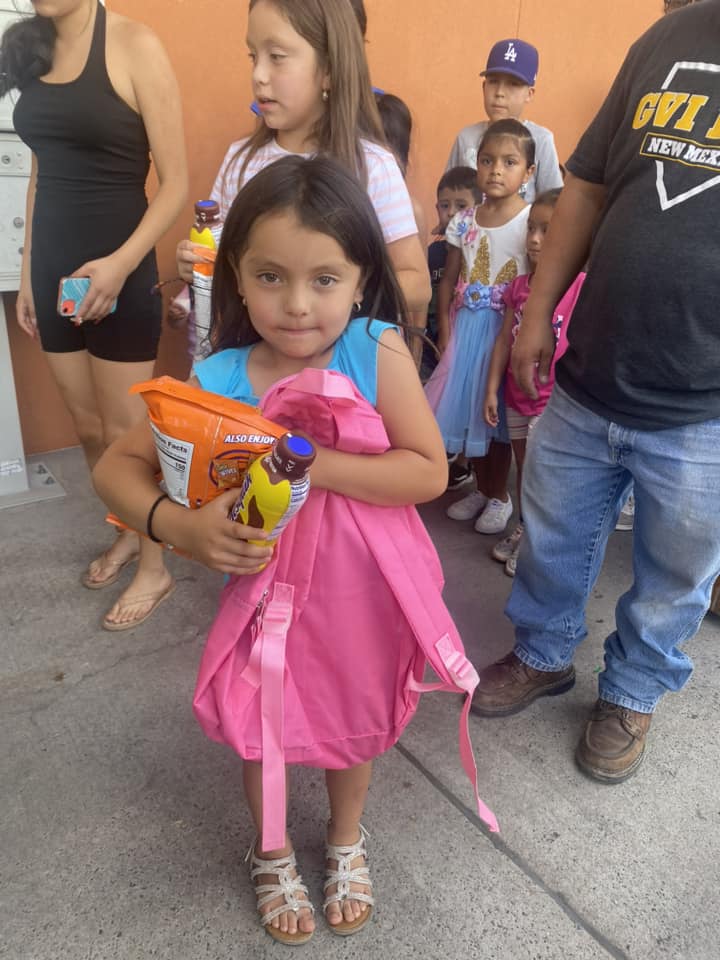 little girl holding snacks and a new backpack